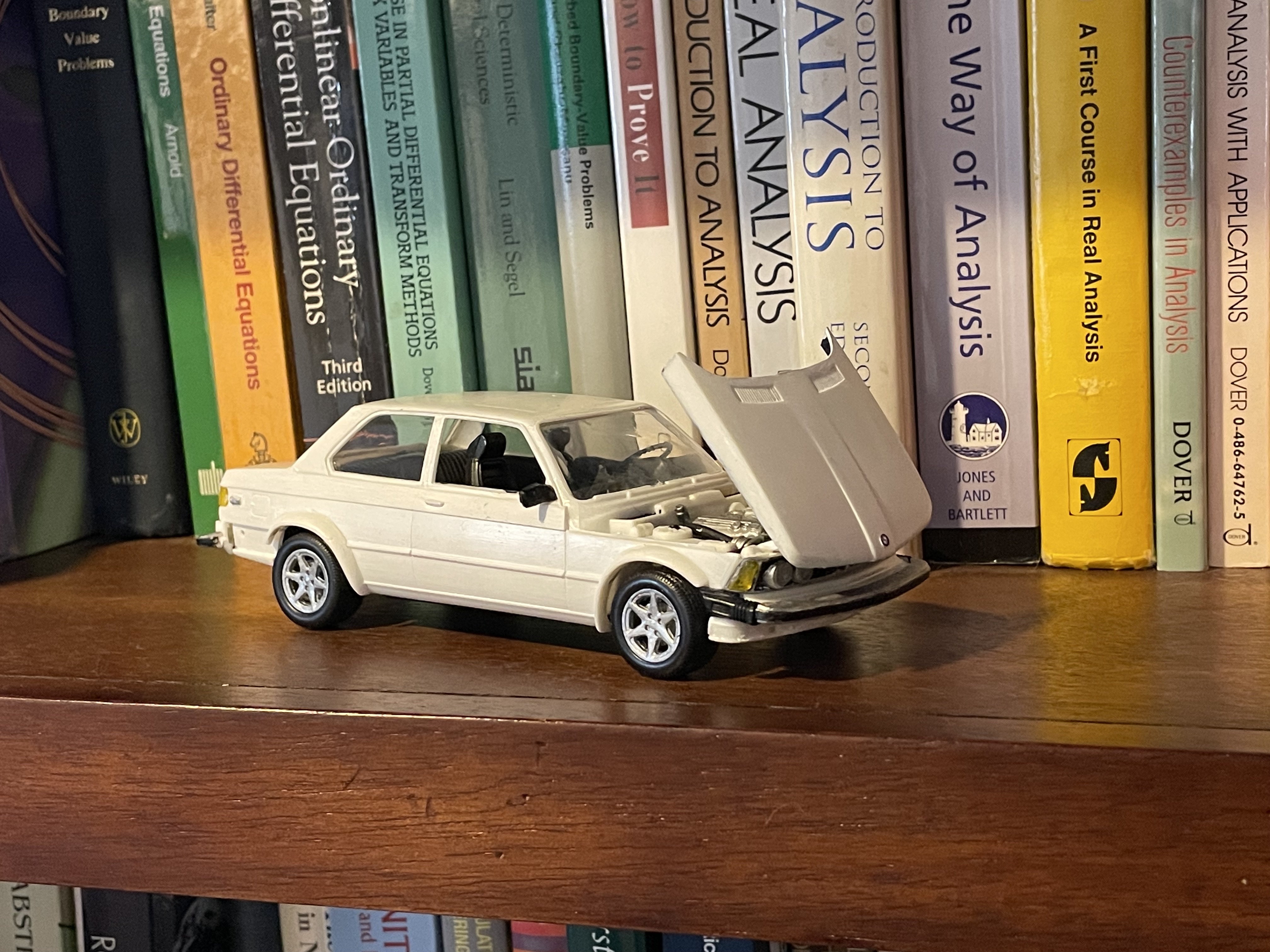 A scale model of a white 1980s BMW, hood open