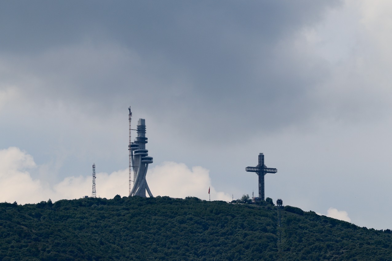 A large cross on top of a mountain, a tower next to it, Skopje