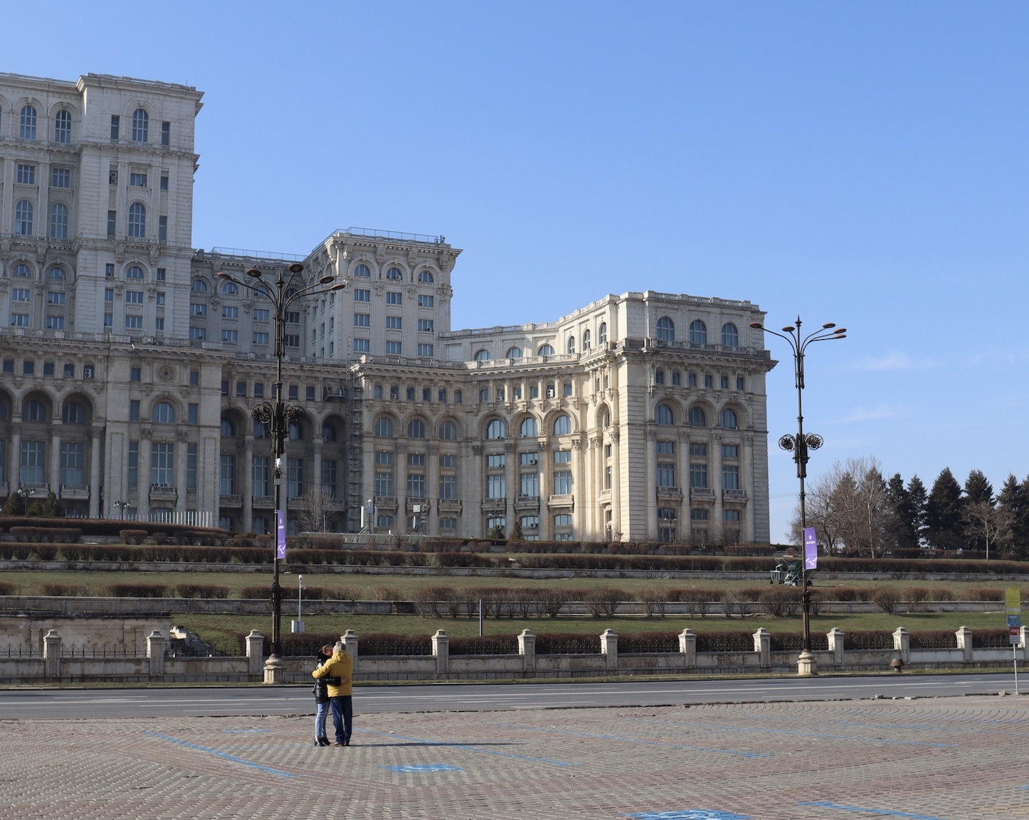 A couple hugs in the plaza in front of Palatul Parlamentului