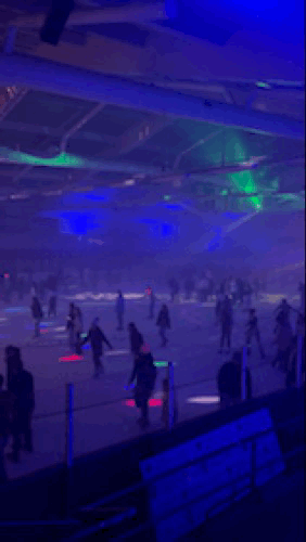 People skate around a colorfully-lit ice rink