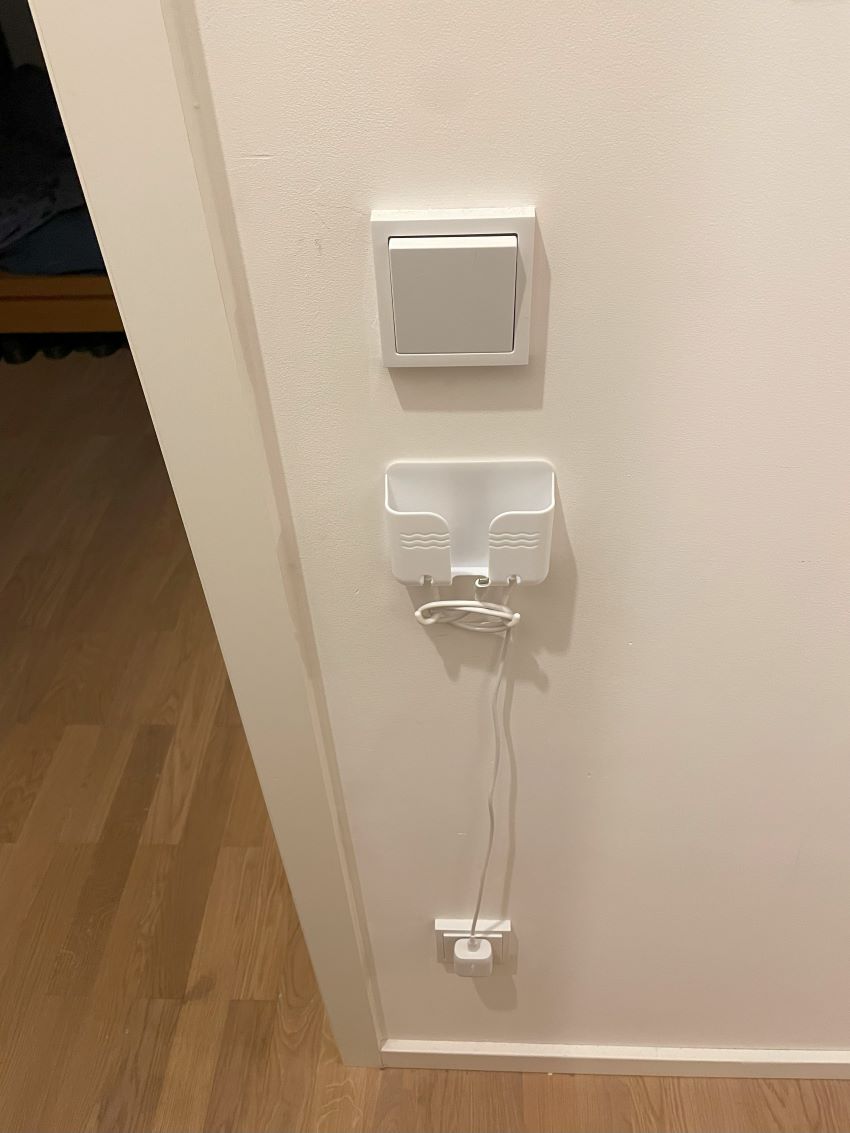 A white plastic phone holder stuck under my lightswitch outside my bedroom